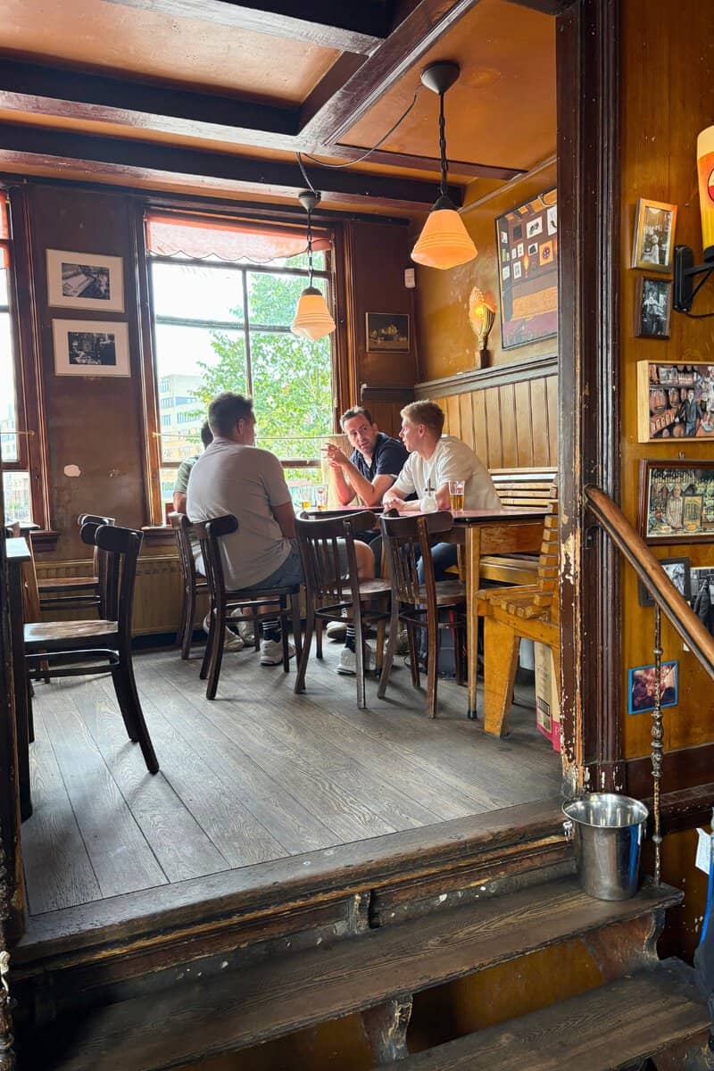 Cafe de Druif in Amsterdam, friends chatting inside at a table.