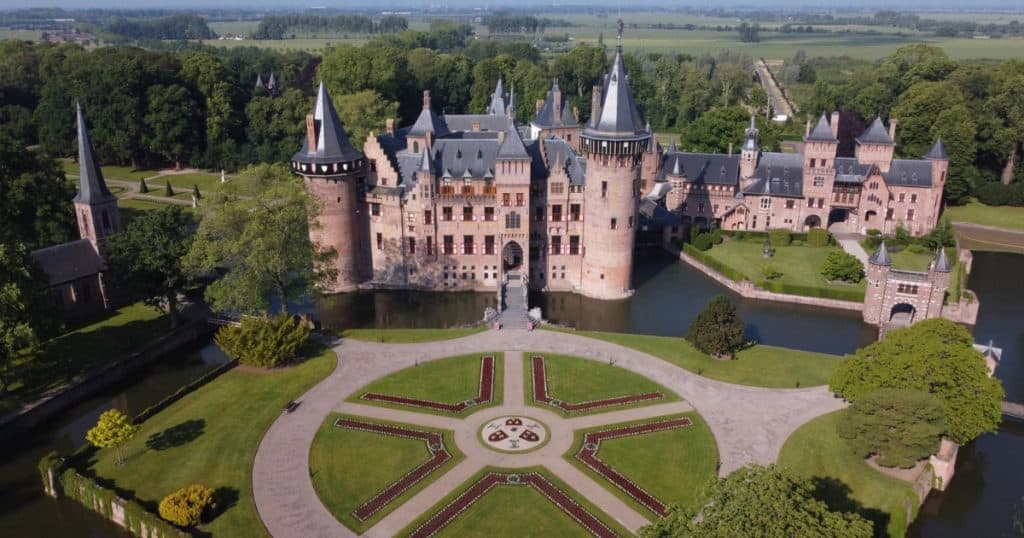 Aerial view of De Haar Castle's full grounds, including the circular garden and the castle framed by open farmland.