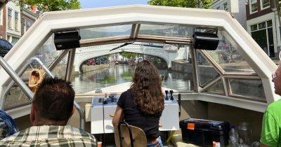 Inside a covered canal tour boat in Delft approaching a bridge.