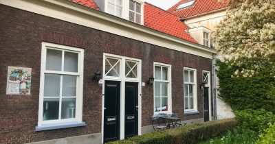 Brick almshouses with a painted gable stone and garden at the Hofje van Almonde in Delft.