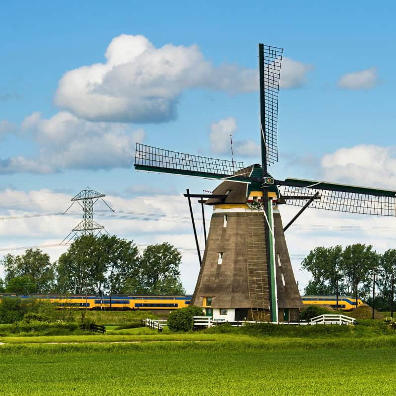 Dutch train in classic Dutch landscape with windmill.