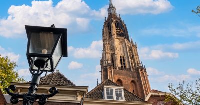 Nieuwe Kerk tower in Delft rising behind an old cast-iron street lamp.